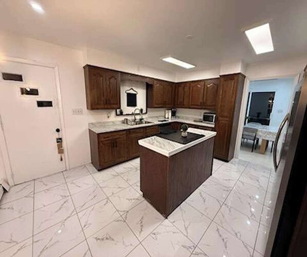 Une cuisine moderne avec un îlot central, des armoires en bois et un sol carrelé.