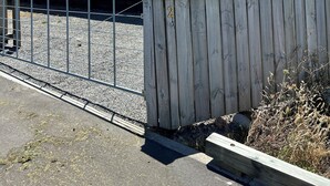 Une maison de plain-pied avec un porche à l’avant, un garage et une cour clôturée.