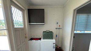 Une petite buanderie comprenant un lave-linge, un sèche-linge et un petit meuble de rangement.