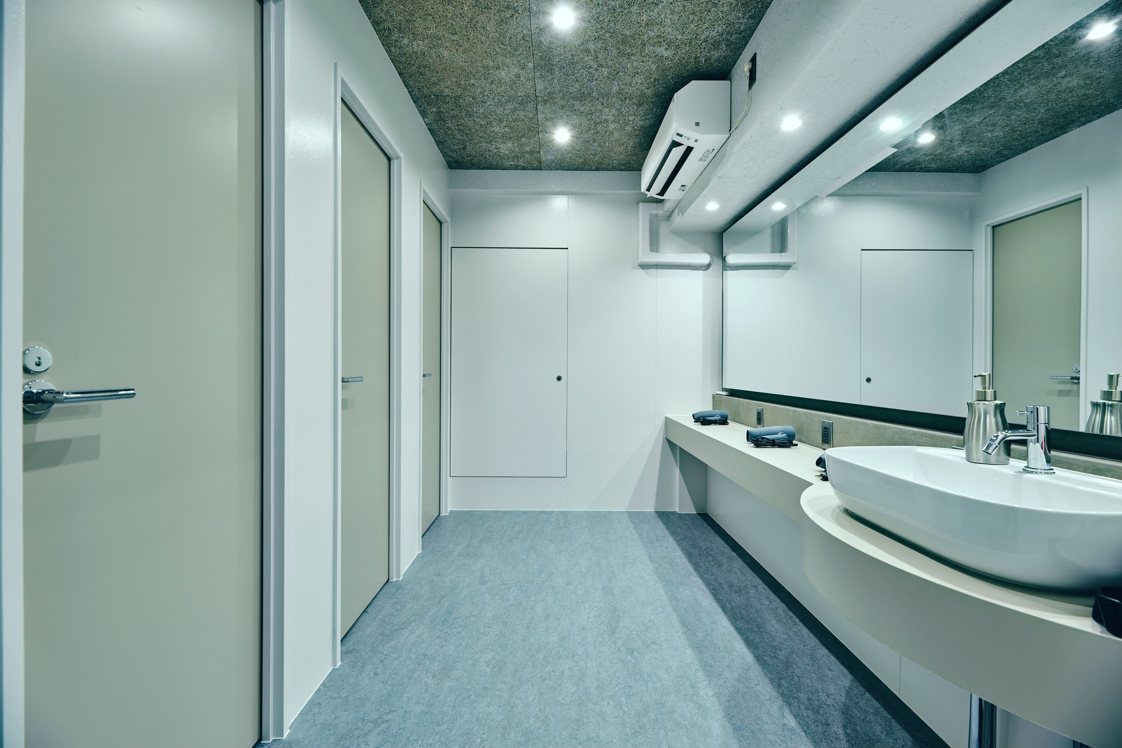 A modern bathroom with a large sink, a mirror, and a door.