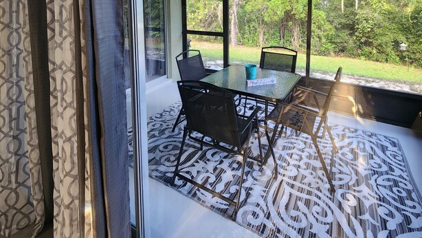 Un espace de restauration moderne doté d’une cloison en verre, d’une table avec des chaises et offrant une vue sur un jardin luxuriant.