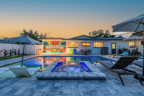 Una piscina con hidromasaje, sillones de descanso y un mural colorido que muestra el texto "LOST IN PARADISE".
