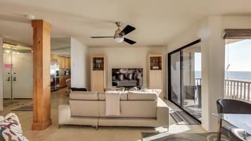 A living room with a sofa, a television, and a balcony with a view.