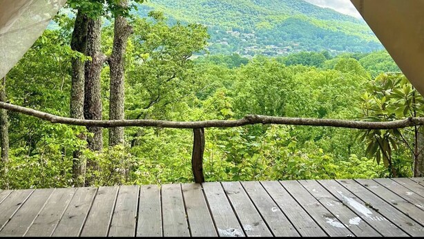A wooden deck with a view of a forested mountain range. - Lover’s Lookout is a treetop retreat  / perfect for a romantic escape. (Waynesville)