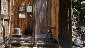 A rustic wooden cabin with a small porch, a metal bucket, and a wooden chair. - Lover’s Lookout is a treetop retreat  / perfect for a romantic escape. (Waynesville)