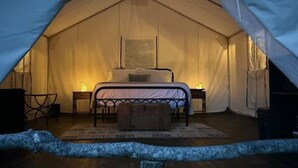 A tent with a bed, bedside tables, and a rug. - Lover’s Lookout is a treetop retreat  / perfect for a romantic escape. (Waynesville)