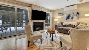 A modern living room with a fireplace, a flat-screen TV, a sofa, and a coffee table.