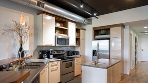 Une cuisine moderne dotée d’appareils électroménagers en acier inoxydable, de meubles en bois et d’un îlot central.