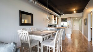 Une cuisine moderne avec des meubles blancs, une table à manger en bois et un îlot central.
