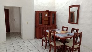 A dining area with a wooden table and chairs, a cabinet, and a mirror on the wall.