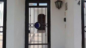 A black metal gate with a blue and white sign, a lantern, and the number 8 on a white wall.