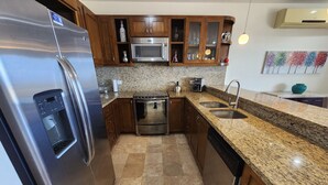 A kitchen with stainless steel appliances, granite countertops, and wooden cabinets. - Condo Ventanas  (Cabo San Lucas)