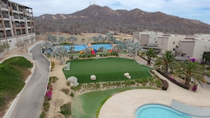 A resort with a swimming pool, a children's play area, and a view of mountains. - Condo Ventanas  (Cabo San Lucas)
