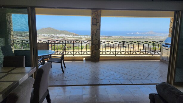 A balcony with a view of the sea, a grill, and a dining area with chairs and a table. - Condo Ventanas  (Cabo San Lucas)
