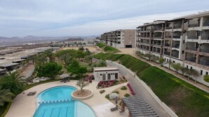A residential area with a swimming pool, landscaped gardens, and multi-story buildings. - Condo Ventanas  (Cabo San Lucas)