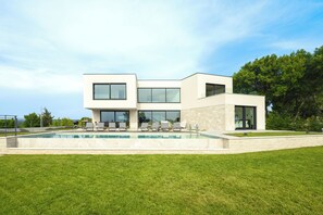 Uma casa moderna de dois andares com piscina, área de estar externa e vista para a paisagem ao redor.
