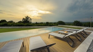 A swimming pool with lounge chairs and a view of the sky.