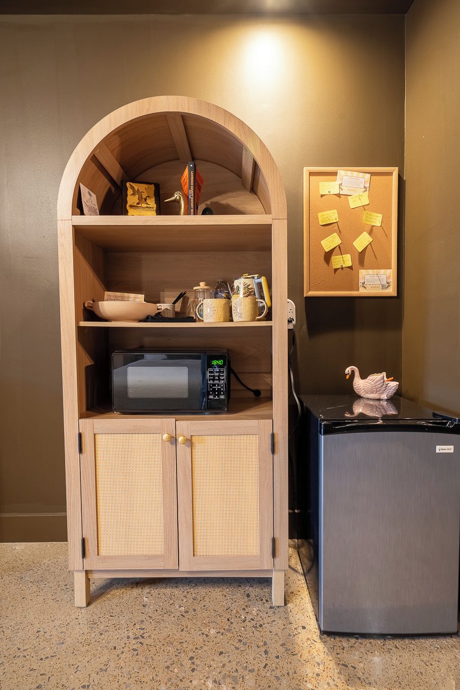 Una kitchenette equipada con microondas, refrigerador y un mueble de madera con estantes.