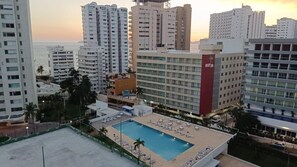 A hotel with a rooftop pool, multiple high-rise buildings, and a view of the ocean at sunset. - 3 bedroom family apartment in Acapulco, a few steps from the beach. (Acapulco de Juárez)