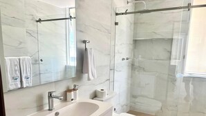 A modern bathroom with a marble sink, toilet, and glass shower enclosure. - 3 bedroom family apartment in Acapulco, a few steps from the beach. (Acapulco de Juárez)