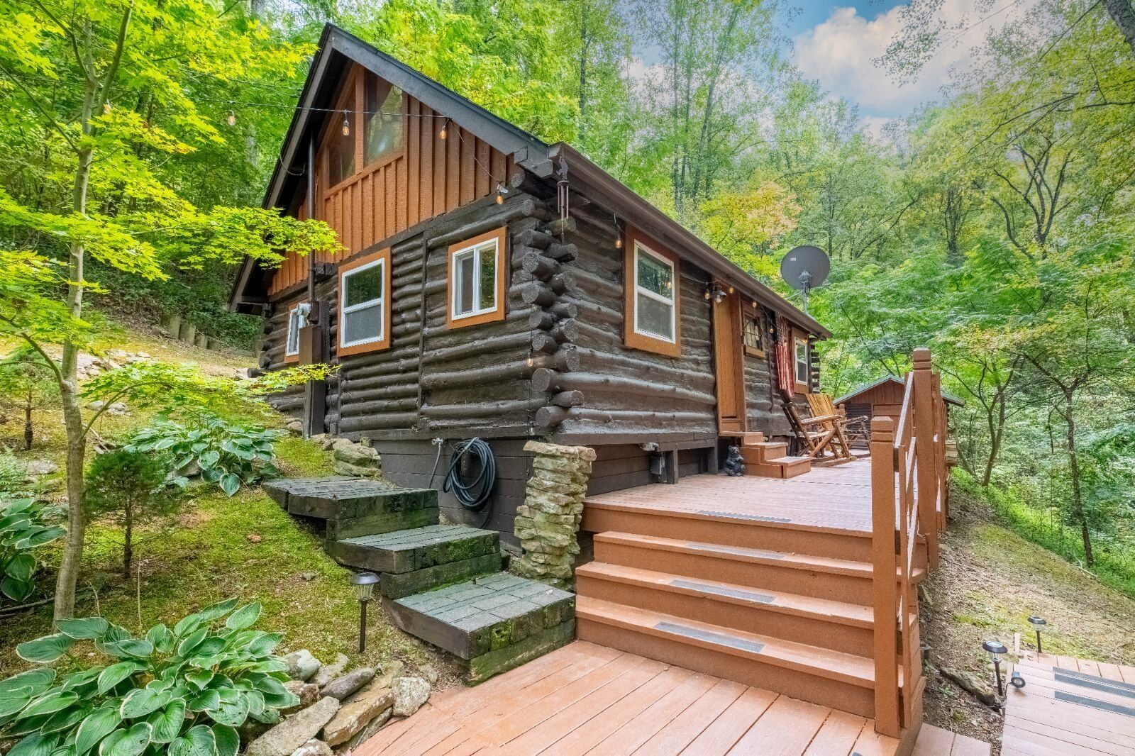 A log cabin with a wooden deck and steps leading up to the entrance.