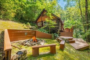 Un chalet rustique doté d’un foyer, de bancs en bois et d’une terrasse.