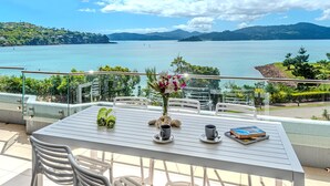 A balcony with a table, chairs, and a vase of flowers.