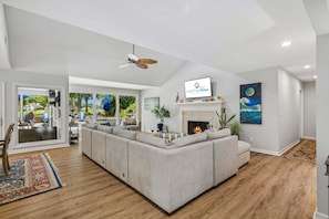 A modern living room with a large sectional sofa, a fireplace, and a television mounted on the wall. - 22 Heath Drive @ Palmetto Dunes | Private Pool | Golf Course View (Hilton Head Island)