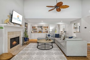 A living room with a fireplace, a sofa, a coffee table, and a ceiling fan.
