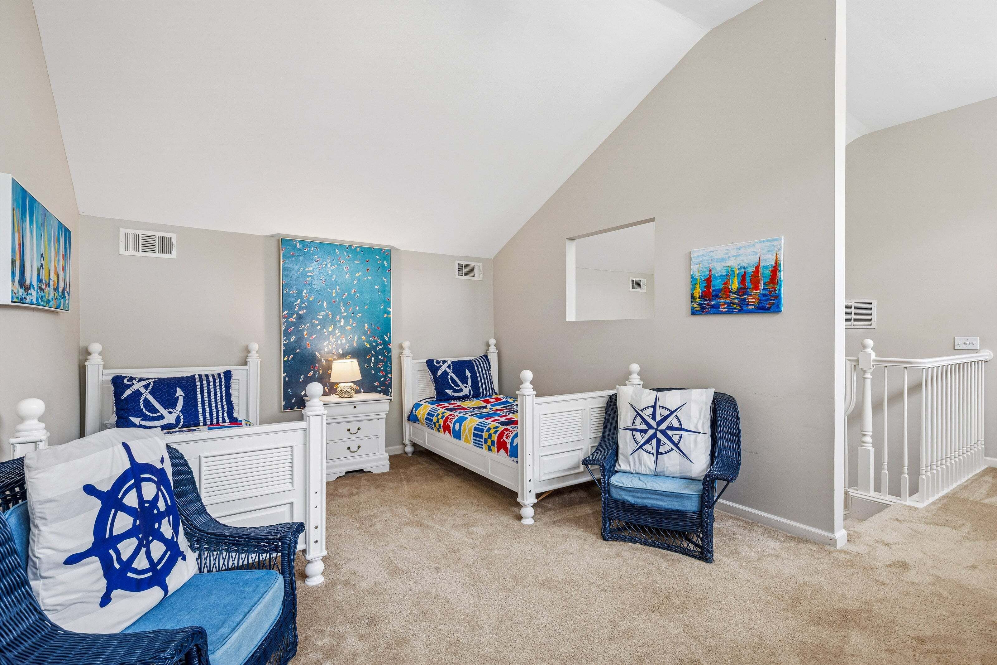 A bedroom with a white bed, a blue and white chair, a large abstract painting, and a small sailboat painting on the wall.