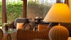 A cozy living room with wicker furniture, a glass coffee table, and a view of greenery outside. - Villa El Ñeru - Bufones de Pría, Llanes (Belmonte De Pria)