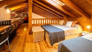 A cozy attic bedroom with a wooden ceiling, a bed with pillows, a small table, and a chair. - Villa El Ñeru - Bufones de Pría, Llanes (Belmonte De Pria)