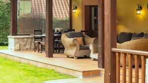 An outdoor patio with wicker furniture, a stone table, and two wall-mounted lights. - Villa El Ñeru - Bufones de Pría, Llanes (Belmonte De Pria)