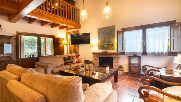 A cozy living room with a fireplace, comfortable seating, and a television. - Villa El Ñeru - Bufones de Pría, Llanes (Belmonte De Pria)