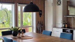 Un coin repas avec une table en bois, des chaises bleues et un grand luminaire suspendu.