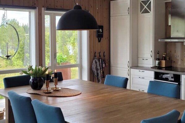 Ein Essbereich mit einem Holztisch, blauen Stühlen und einer großen Pendelleuchte.