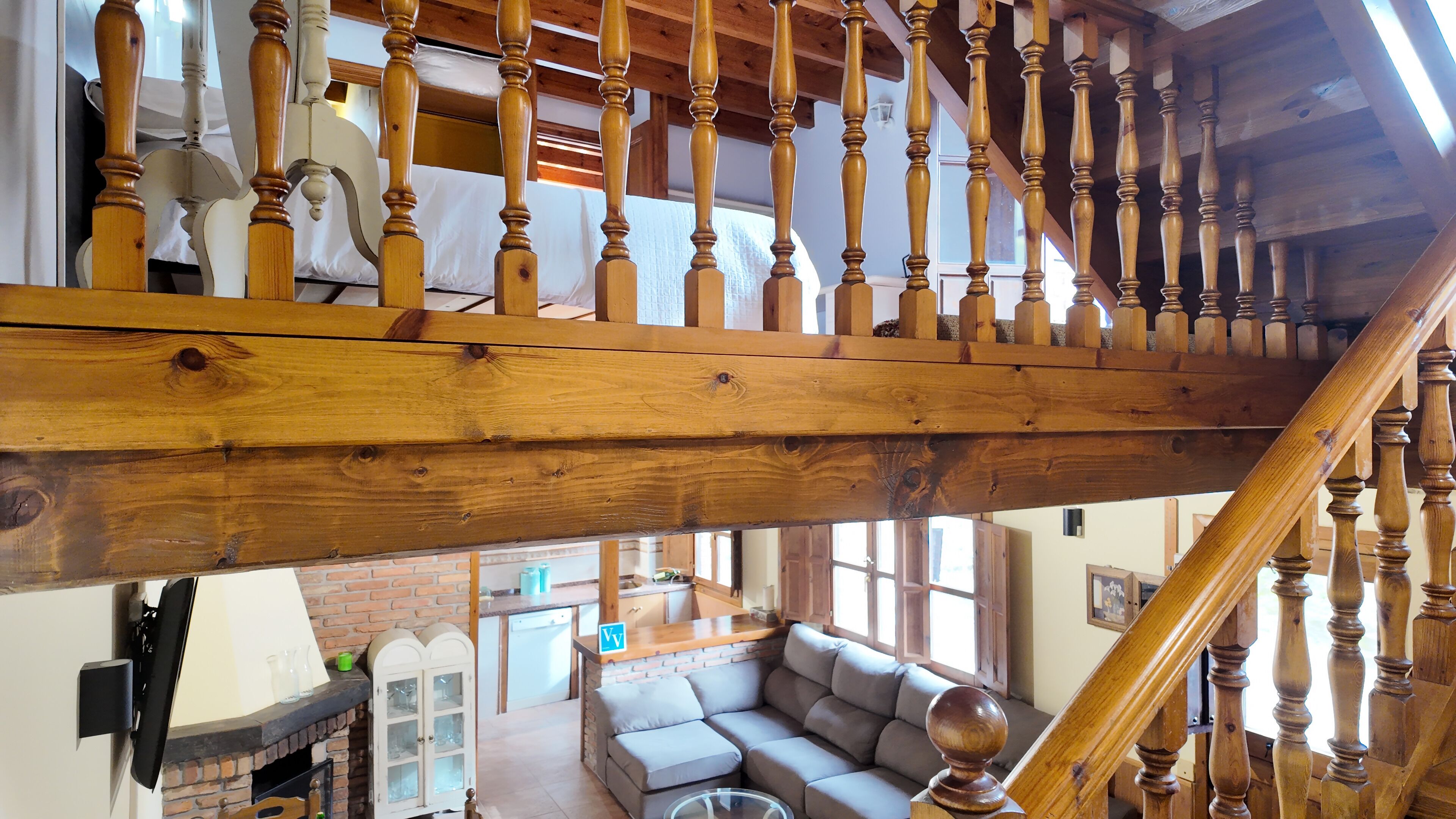 Uma escada de madeira com vista para uma sala de estar, incluindo um sofá e uma lareira.
