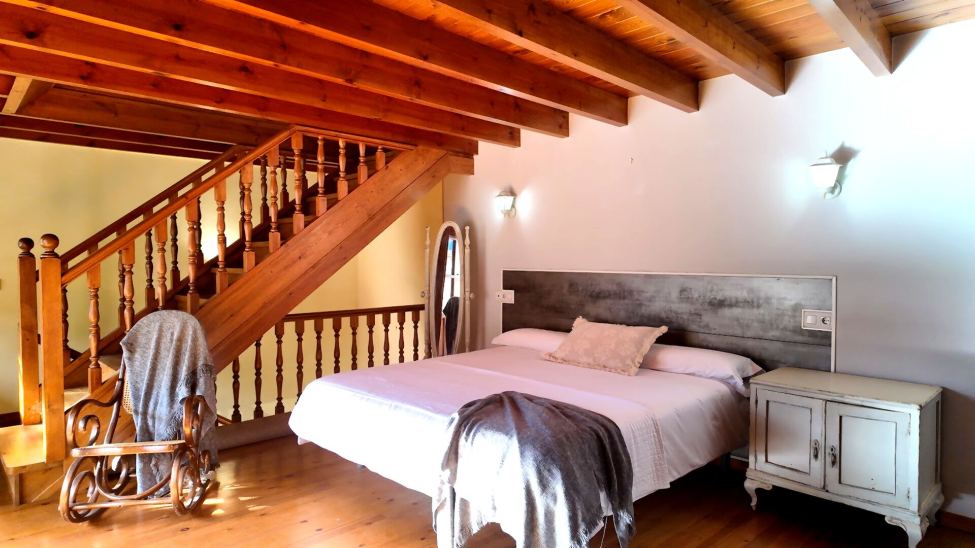Ein Schlafzimmer mit einer Holztreppe, einem Bett mit Kopfteil, einem Nachttisch und einem Kleiderschrank.