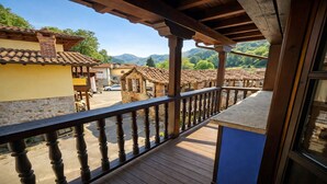 A balcony with a wooden railing overlooking a village with traditional buildings and mountains in the background. - El Rincón de Soto - Covadonga and Cangas de Onís (Cangas De Onis)
