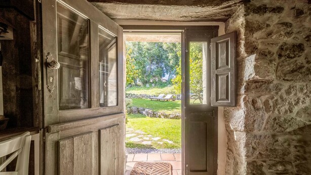 An open door leading to a garden with a stone wall and a wooden bench. - Llanes House with Garden - La Casa del Güelu (Hontoria)