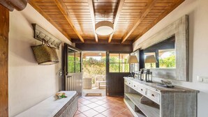 A bathroom with a wooden ceiling, a bench, a sink with a mirror, and a view of the outdoors. - Llanes House with Garden - La Casa del Güelu (Hontoria)