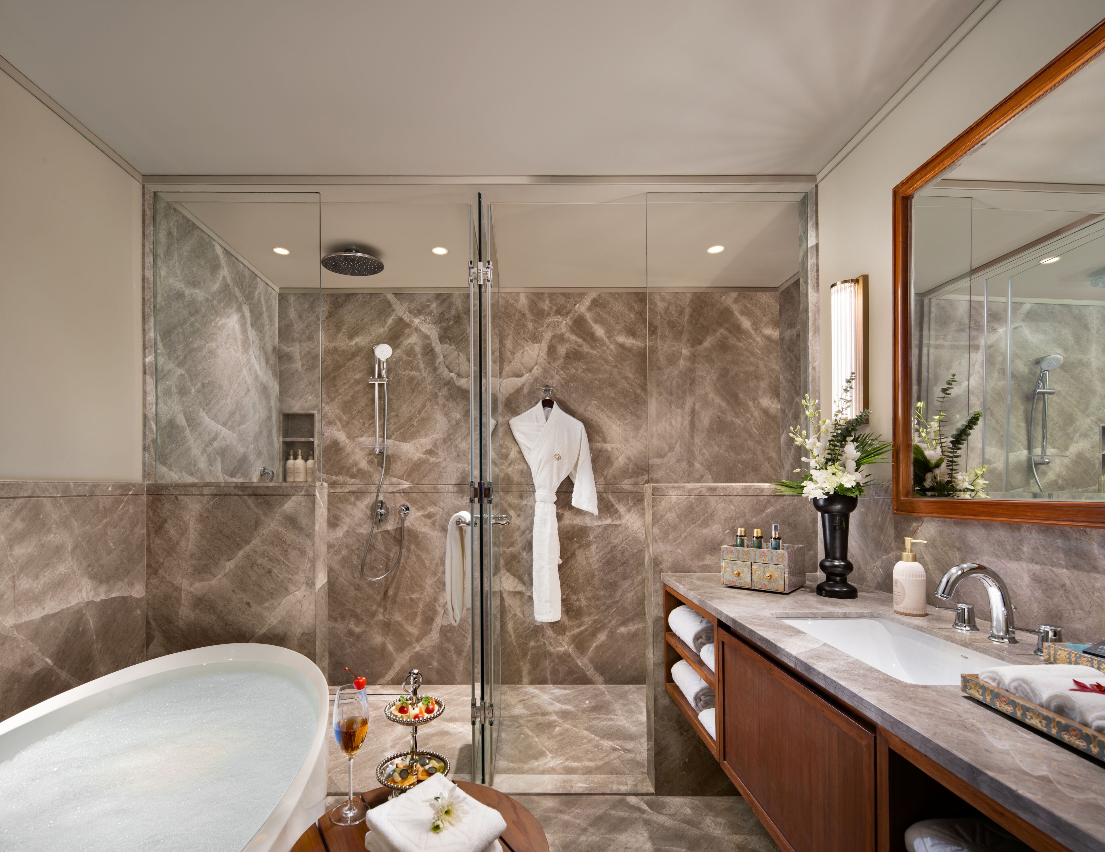 A modern bathroom with a glass-enclosed shower, a freestanding bathtub, and a vanity with a large mirror.