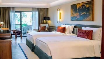 A hotel room with two beds, a desk, a chair, a lamp, and a painting on the wall.