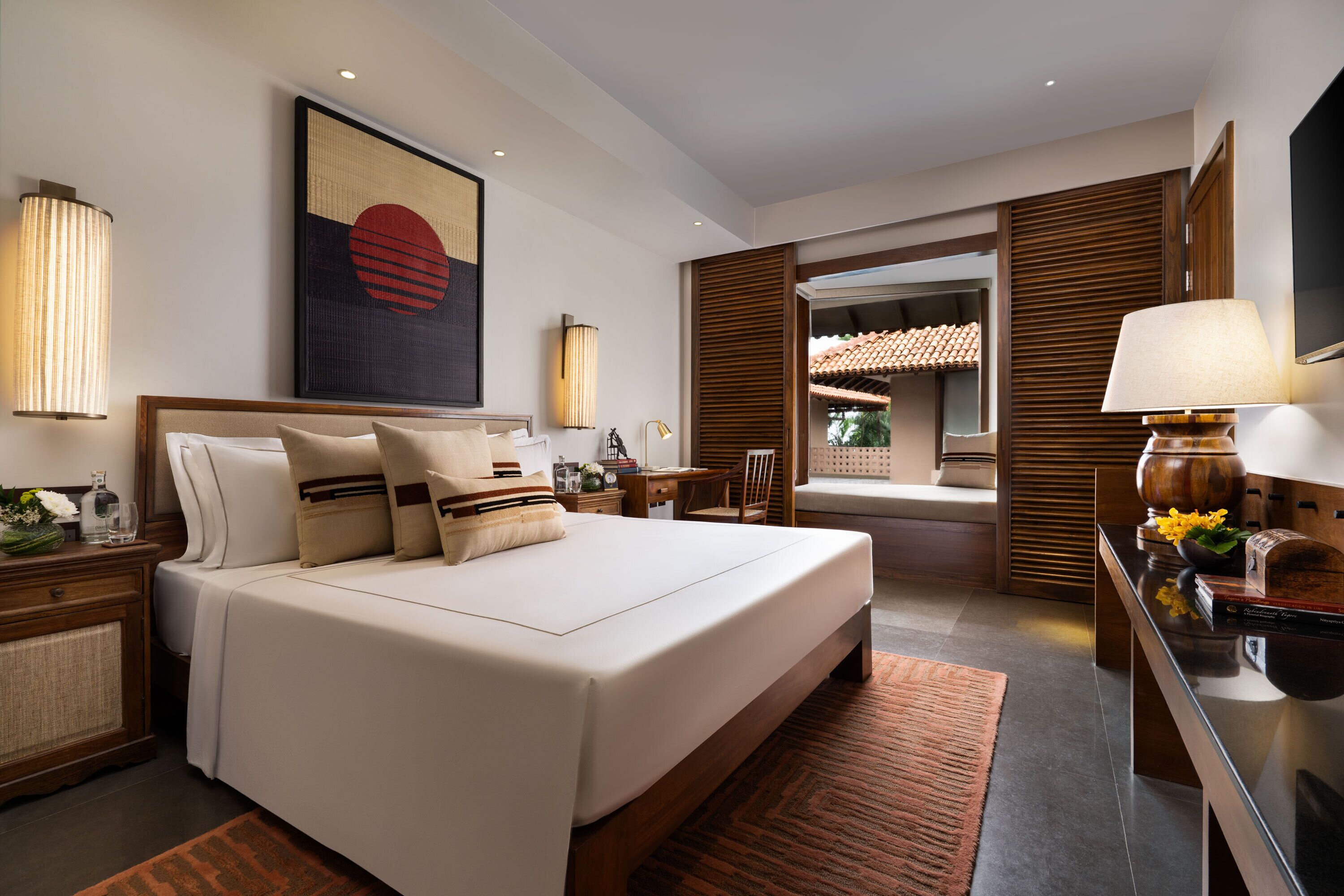 Una habitación de hotel moderna con una cama grande, cabecera de madera y vista a un patio.