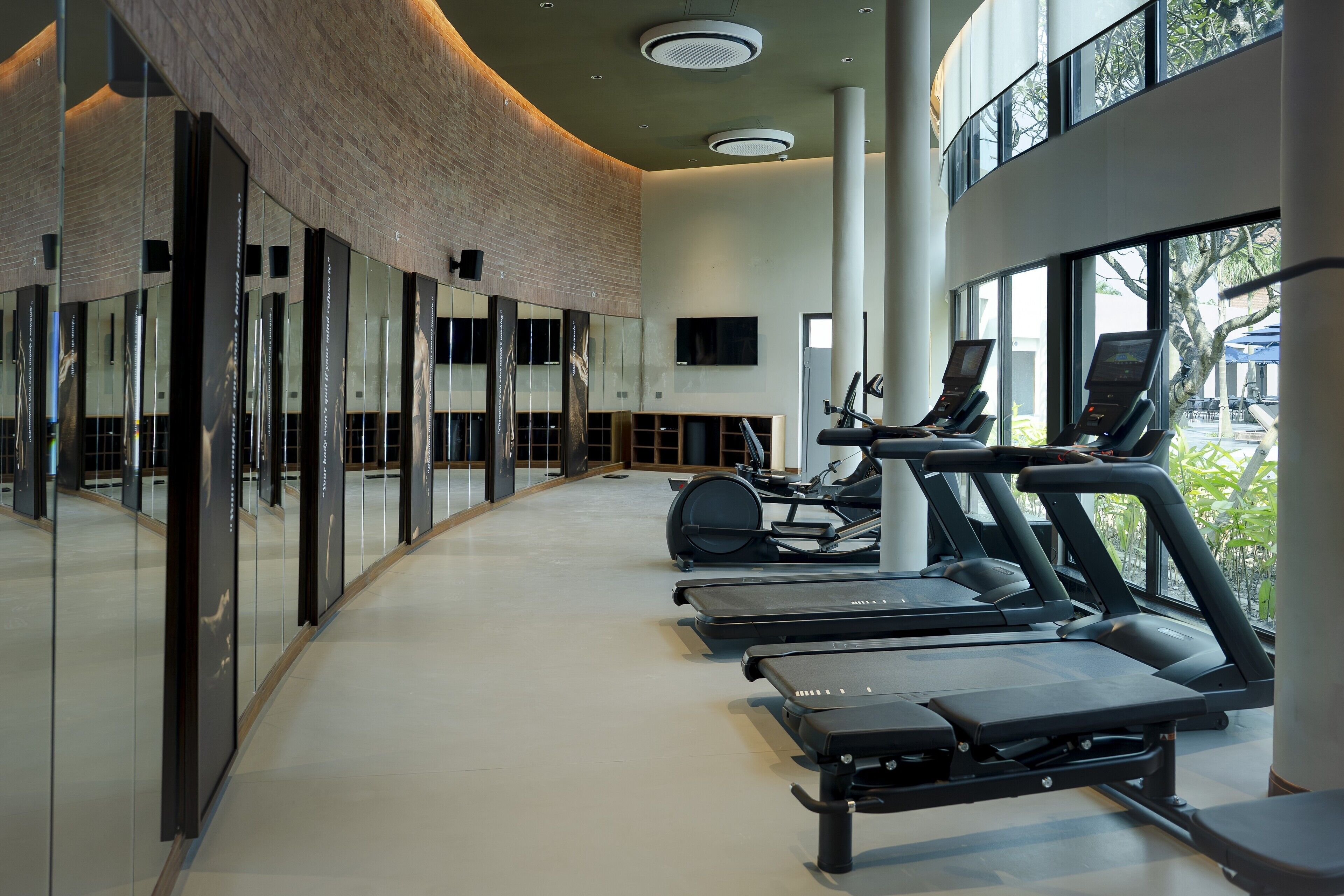 Et moderne fitnesscenter med løbebånd, motionscykler og en stor spejlvæg.