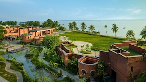 Un resort con varias construcciones, un patio central y vista al mar.