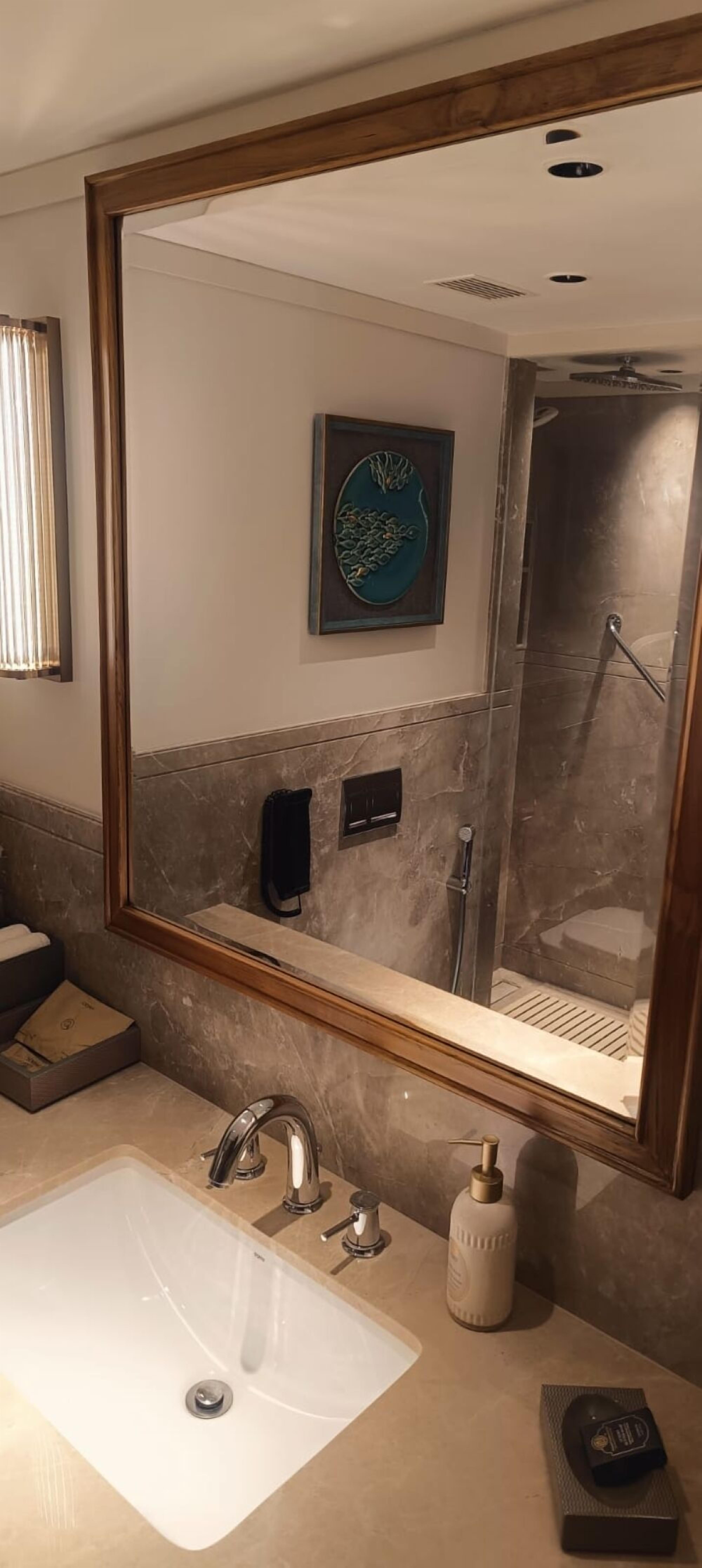 A bathroom with a large mirror, a sink, a shower, and a towel rack.