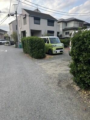 Uma carrinha verde estacionada numa entrada de garagem, com uma casa ao fundo.