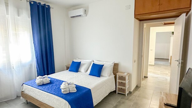 A hotel room with a bed, a nightstand, an air conditioning unit, and a wooden wardrobe. - aMare Apartment, cozy accommodation a few steps from the sea (Nettuno)