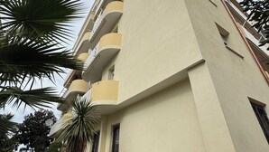 A multi-story building with balconies, surrounded by potted plants and trees. - aMare Apartment, cozy accommodation a few steps from the sea (Nettuno)